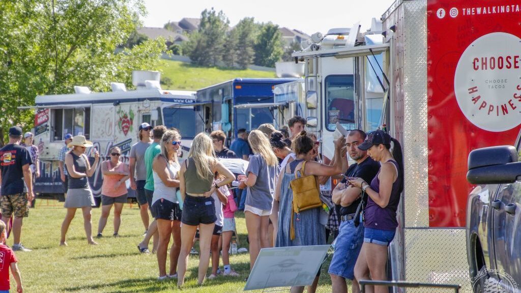 Groups of people gathered around food trucks.