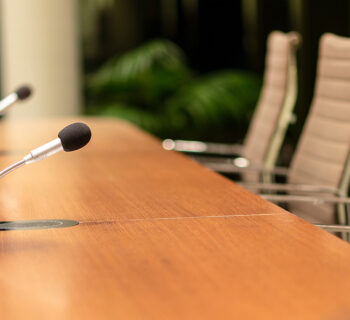 Empty chairs at a table with microphones.