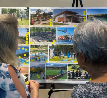 Two women review a display board at a public meeting.