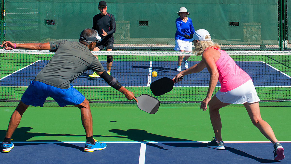 A group of four people playing pickleball.