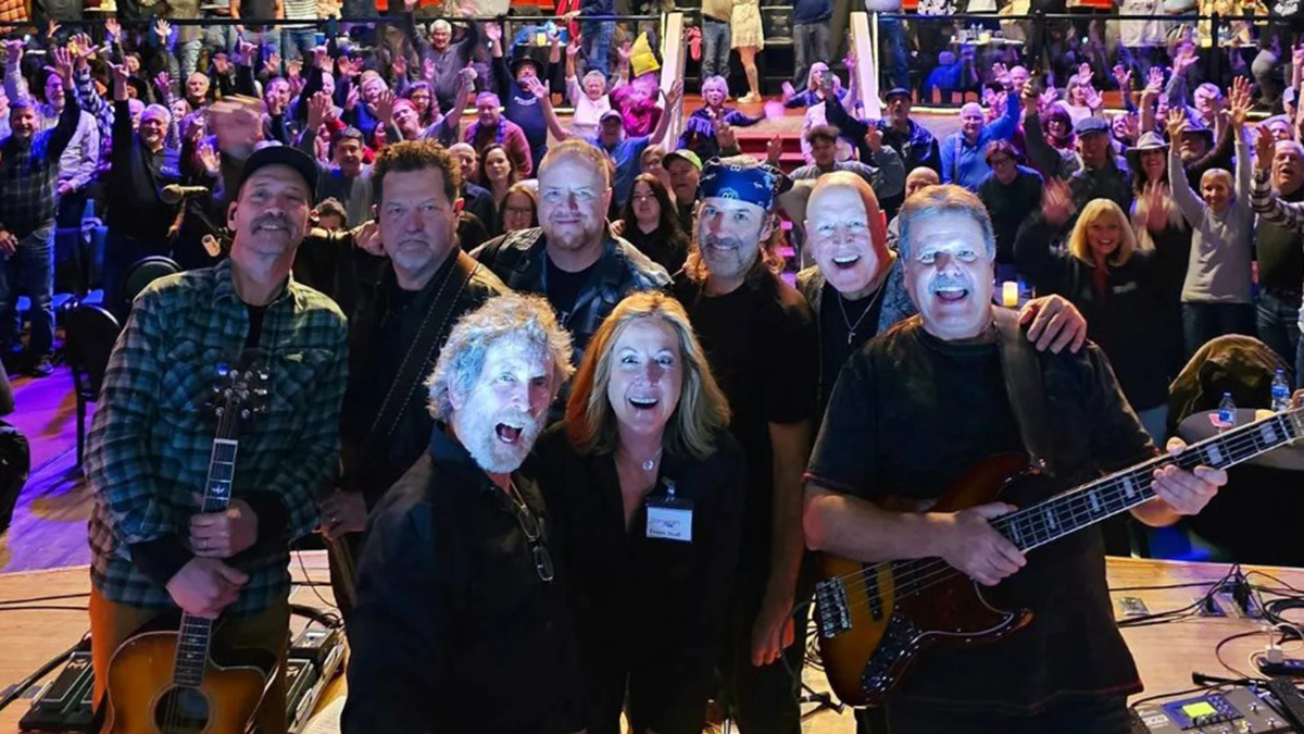 The Long Run band members posing on a stage.