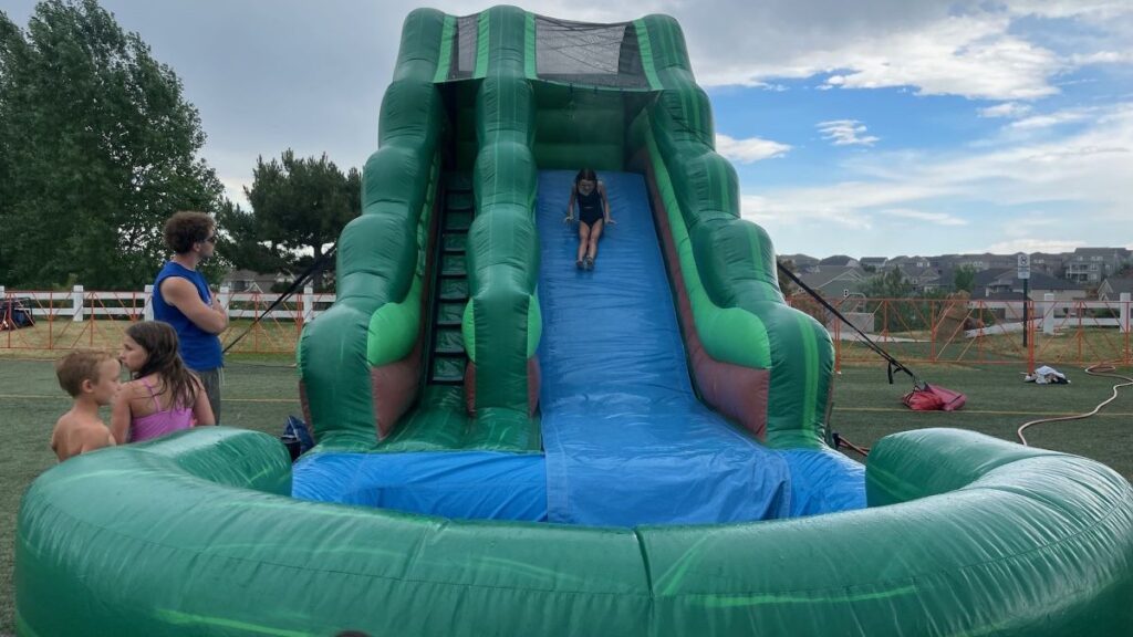 Child sliding down a large green and blue water slide.