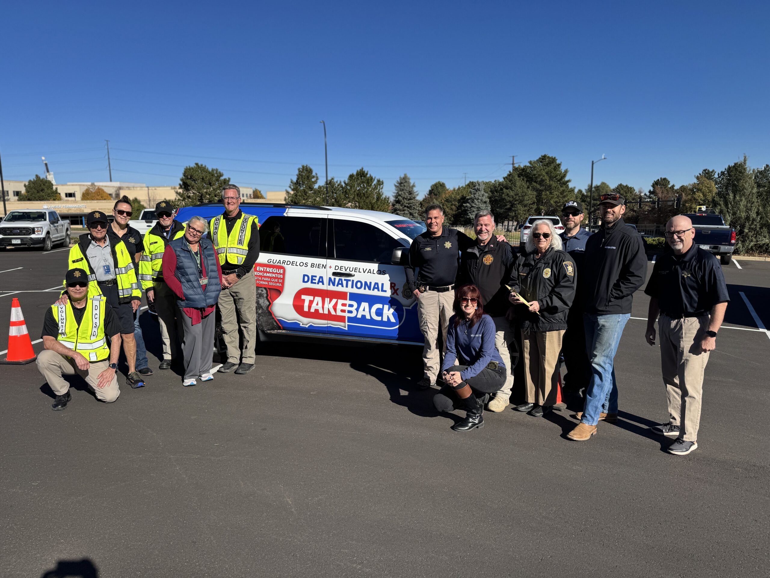 Douglas County Sheriff's Office employees gather for a photo in front of a vehicle during a National Drug Take Back Day event.