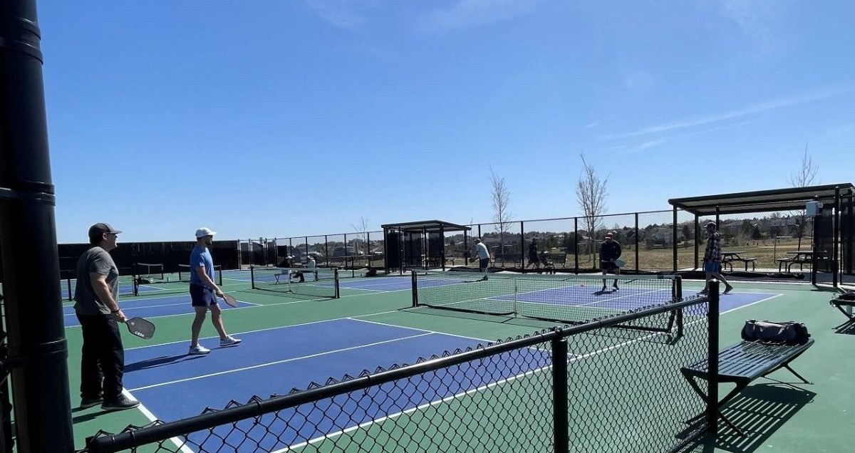 Four people playing pickleball on an outdoor court.