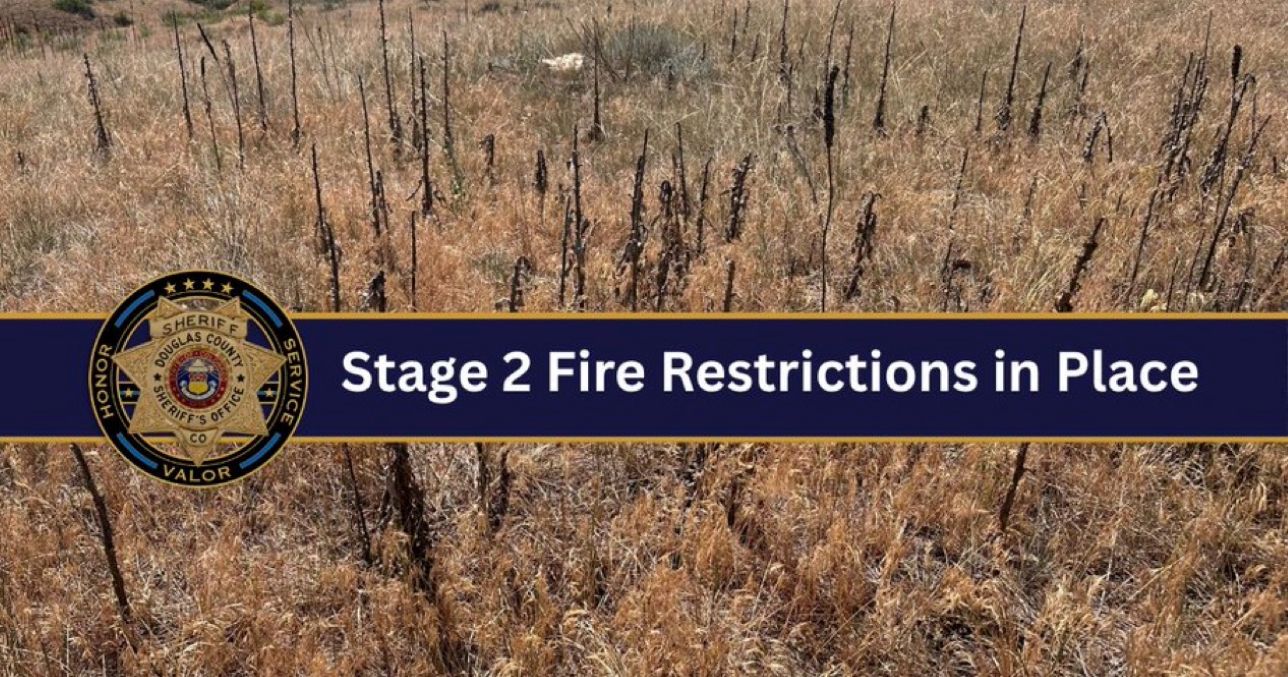 Brown grass and brush with a blue banner that reads "Stage 2 Fire Restrictions". The Douglas County Sheriff's logo is also on the banner.